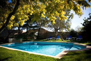 Una piscina al aire libre, sillones reclinables de piscina
