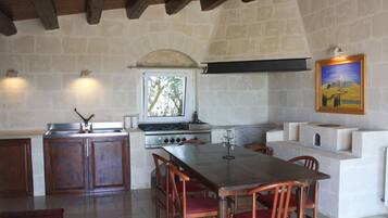 Una cocina rústica con pared de piedra, armarios de madera, una amplia mesa de comedor y un cuadro en la pared.