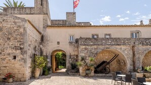 Un patio con muros de piedra, arcos y una bandera.