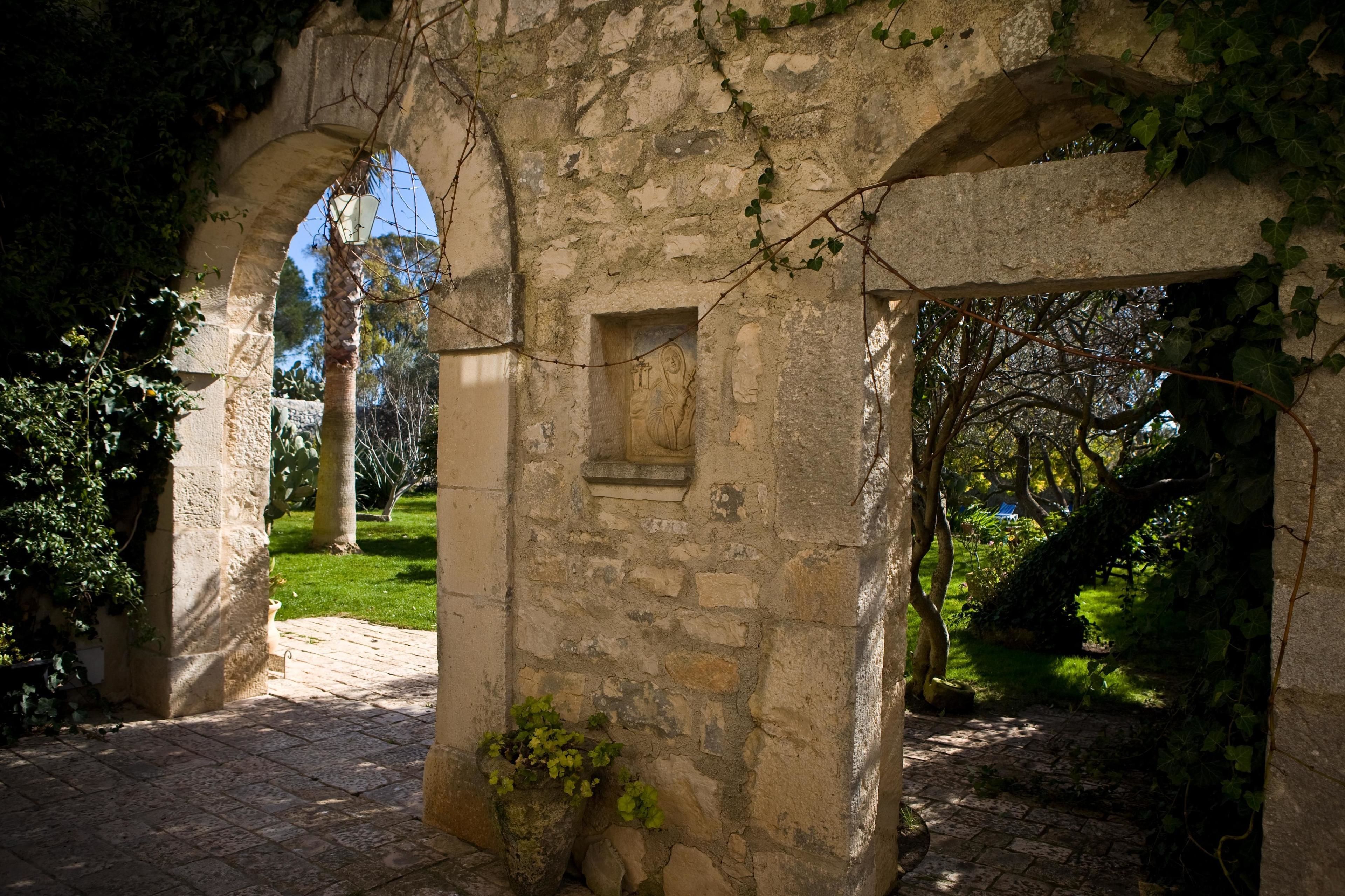 An ancient stone structure with arches, a small window, and a potted plant.