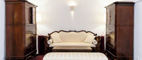 A room with a sofa, a matching ottoman, and two wooden cabinets.