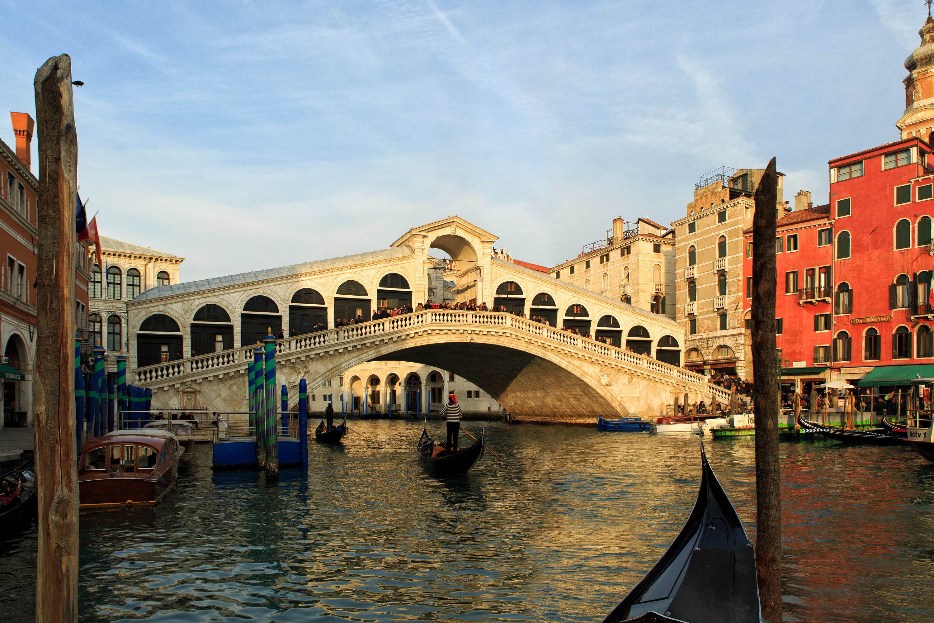 A historic stone bridge over a canal with gondolas, surrounded by traditional Venetian buildings.