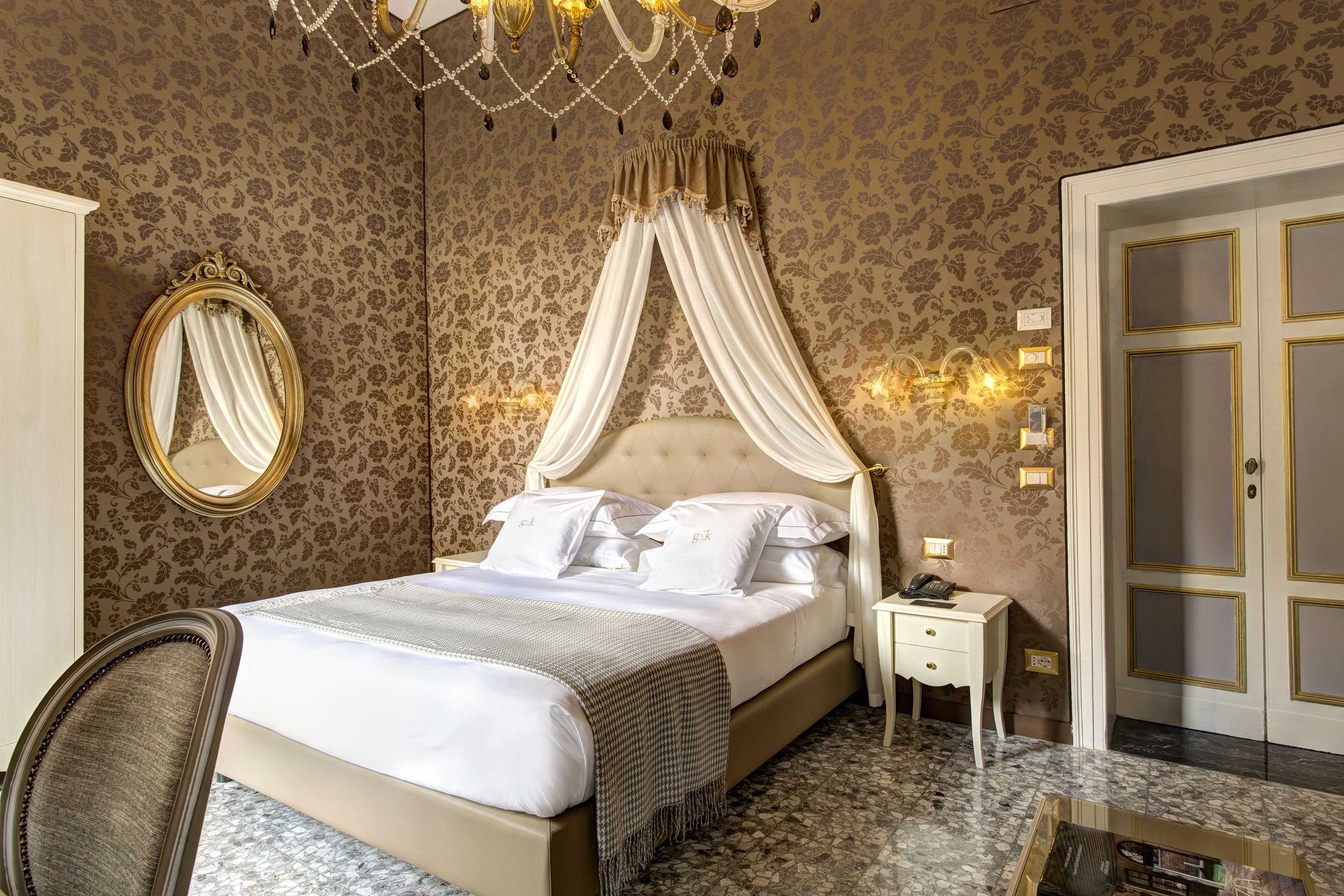 A well-appointed bedroom with a four-poster bed, a bedside table with a lamp, and a large mirror.