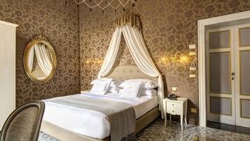 A well-appointed bedroom with a four-poster bed, a bedside table with a lamp, and a large mirror.