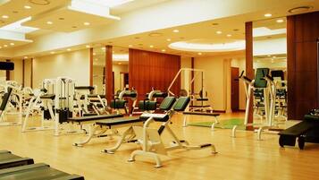 Une salle de sport spacieuse, dotée de divers appareils d’exercice, notamment des tapis de course et des appareils de musculation, disposés dans un espace ouvert.