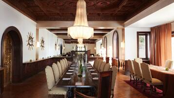 A formal dining room with a long table, multiple chairs, and a chandelier.