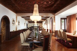 A formal dining room with a long table, multiple chairs, and a chandelier.
