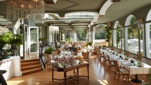 A spacious dining area with high ceilings, large windows, and elegant chandeliers. - Brindos, Lac & Château (Anglet)