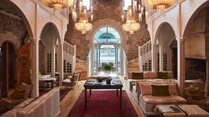 A spacious lobby with a grand staircase, elegant chandeliers, and comfortable seating areas. - Brindos, Lac & Château (Anglet)