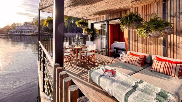 A wooden deck with a sofa and chairs, overlooking a body of water. - Brindos, Lac & Château (Anglet)