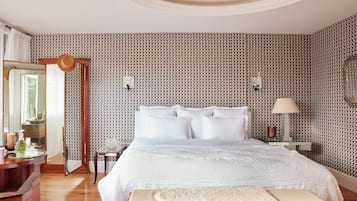 Un dormitorio con una cama grande, una mesita de noche con lámpara, un espejo y una cómoda.