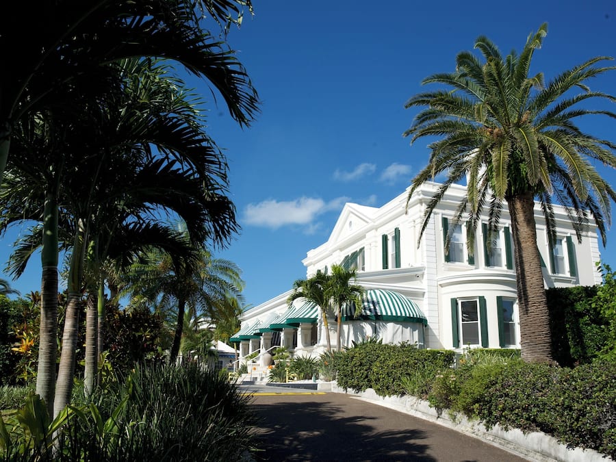 Un edificio grande y blanco con toldos verdes y palmeras al frente.