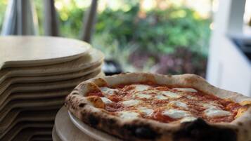 Una pizza sobre una tabla de madera con un fondo desenfocado al aire libre.
