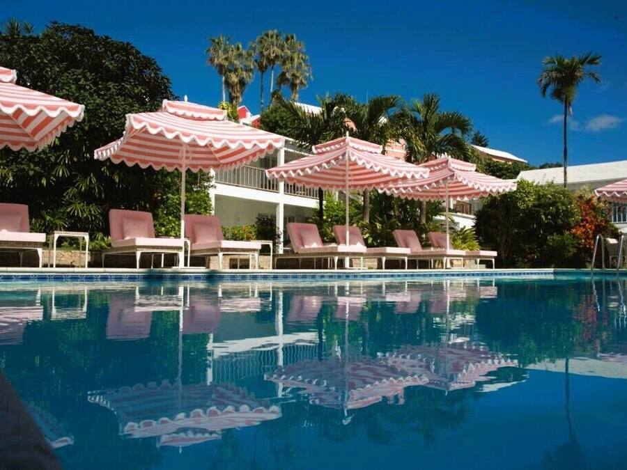 A pool area with pink-striped umbrellas and lounge chairs.