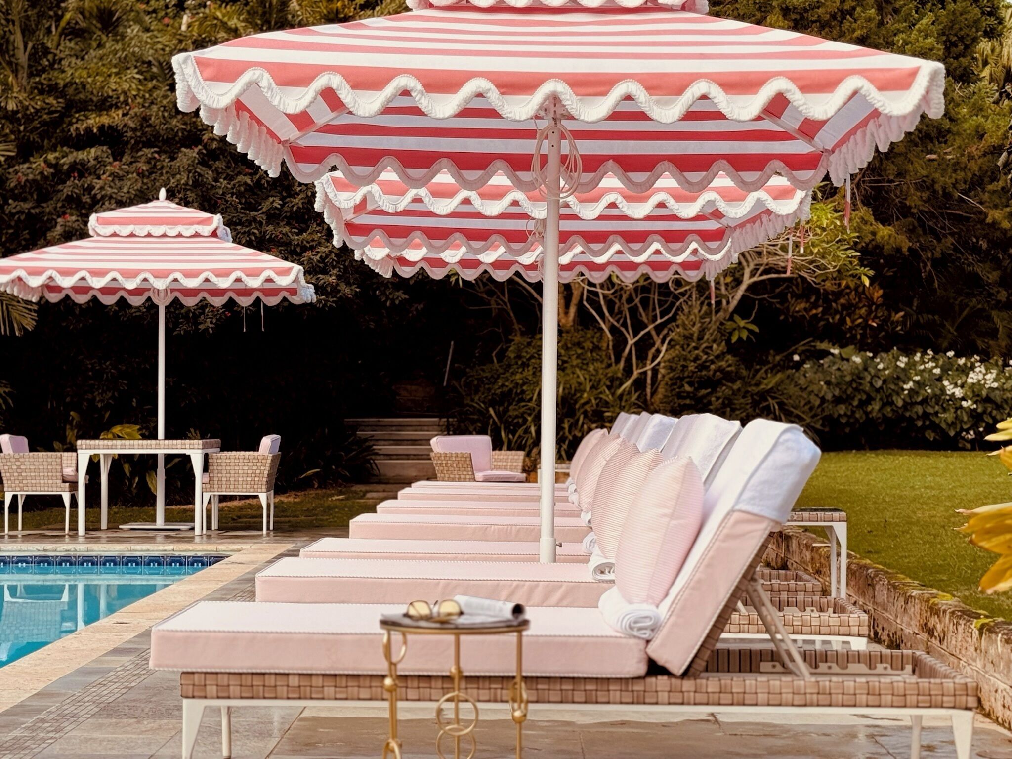 A poolside area with lounge chairs and striped umbrellas.