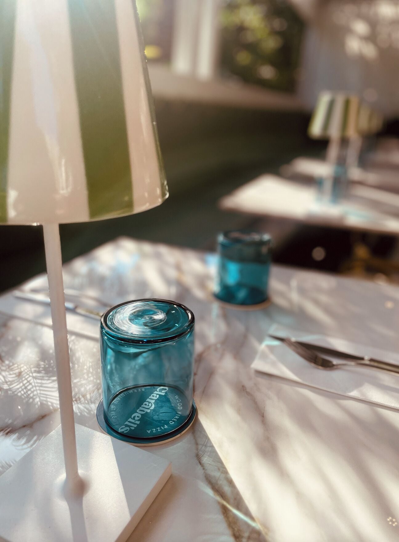 Una mesa con mantel blanco, una vela azul y un candelabro con etiqueta.