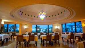 A restaurant with multiple tables and chairs, large windows, and a chandelier. - Hotel Fiesta Beach Djerba (Djerba Midun)