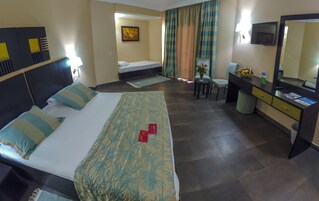 A hotel room with a bed, a desk, a chair, a TV, and a bathroom.