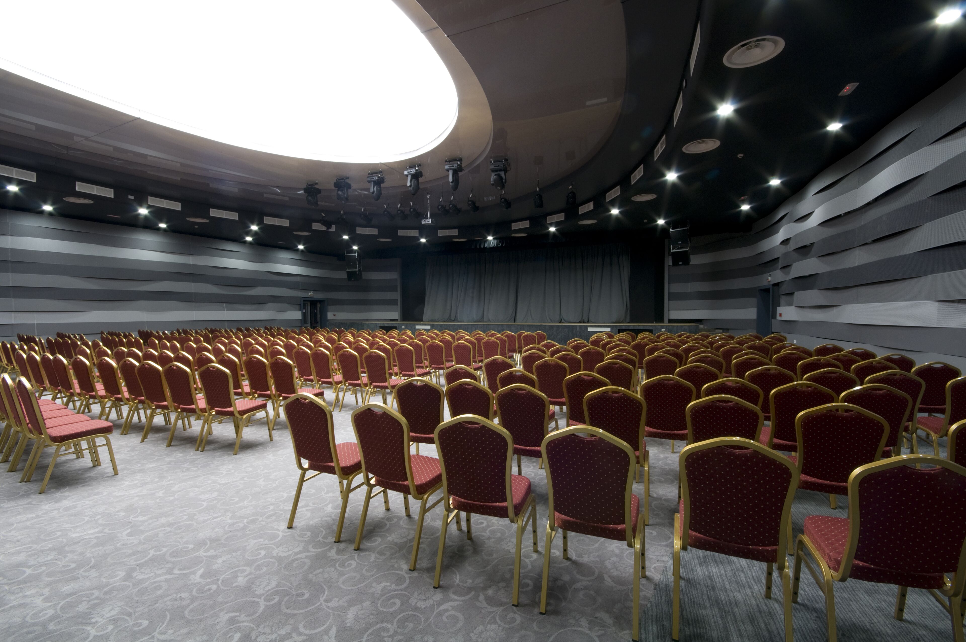 Ein Konferenzraum mit Reihen roter Stühle und einer Bühne.
