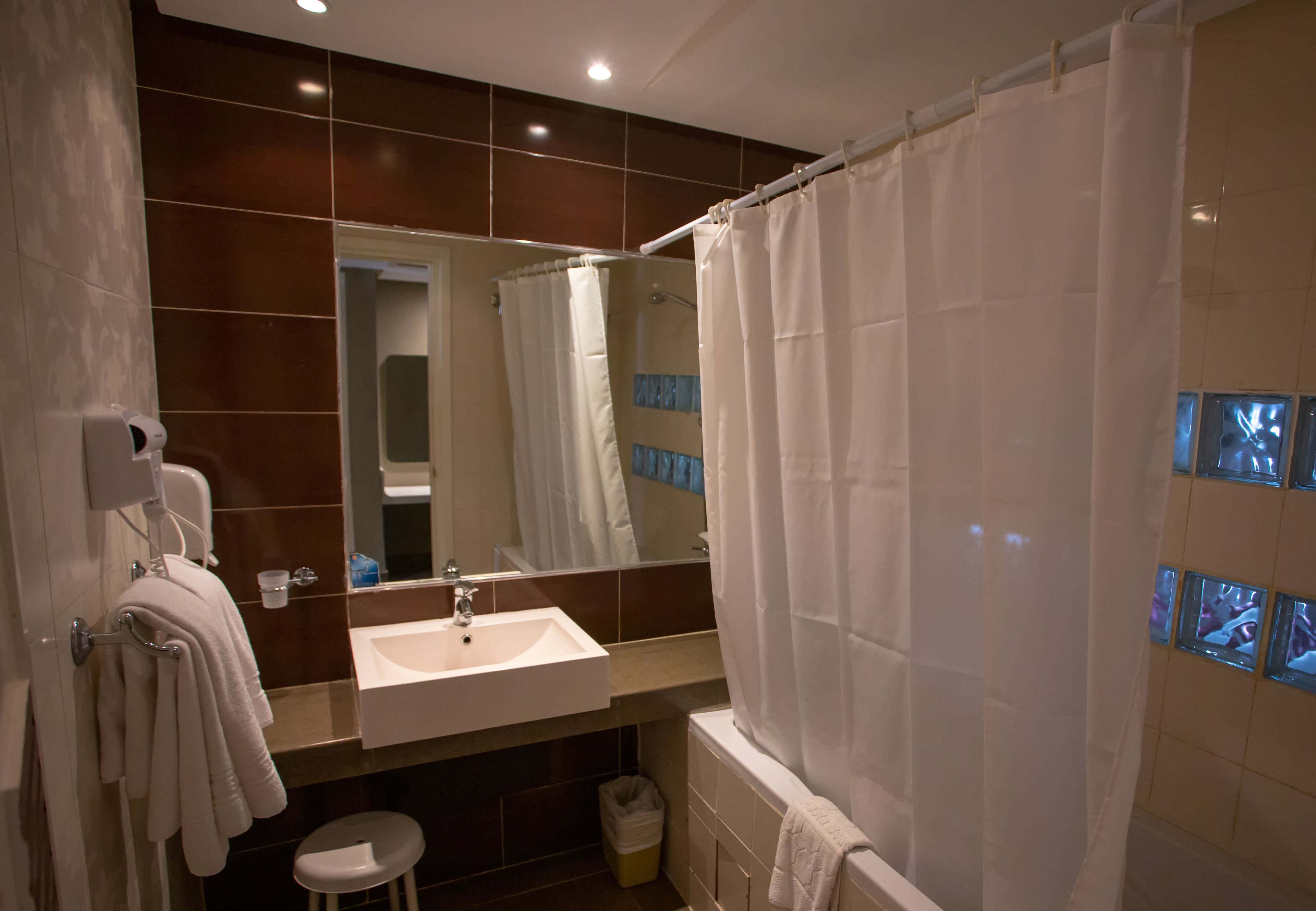 A modern bathroom with a sink, mirror, and shower curtain.