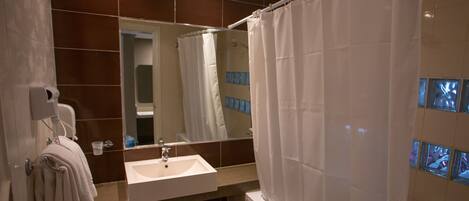 A modern bathroom with a sink, mirror, and shower curtain.