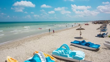 Praia particular, areia branca, espreguiçadeiras, guarda-sóis