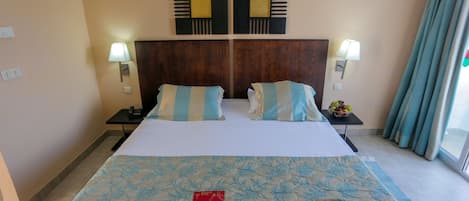 Habitación de hotel con una cama grande, dos mesitas de noche, un cabecero de madera y dos lámparas fijadas a la pared.