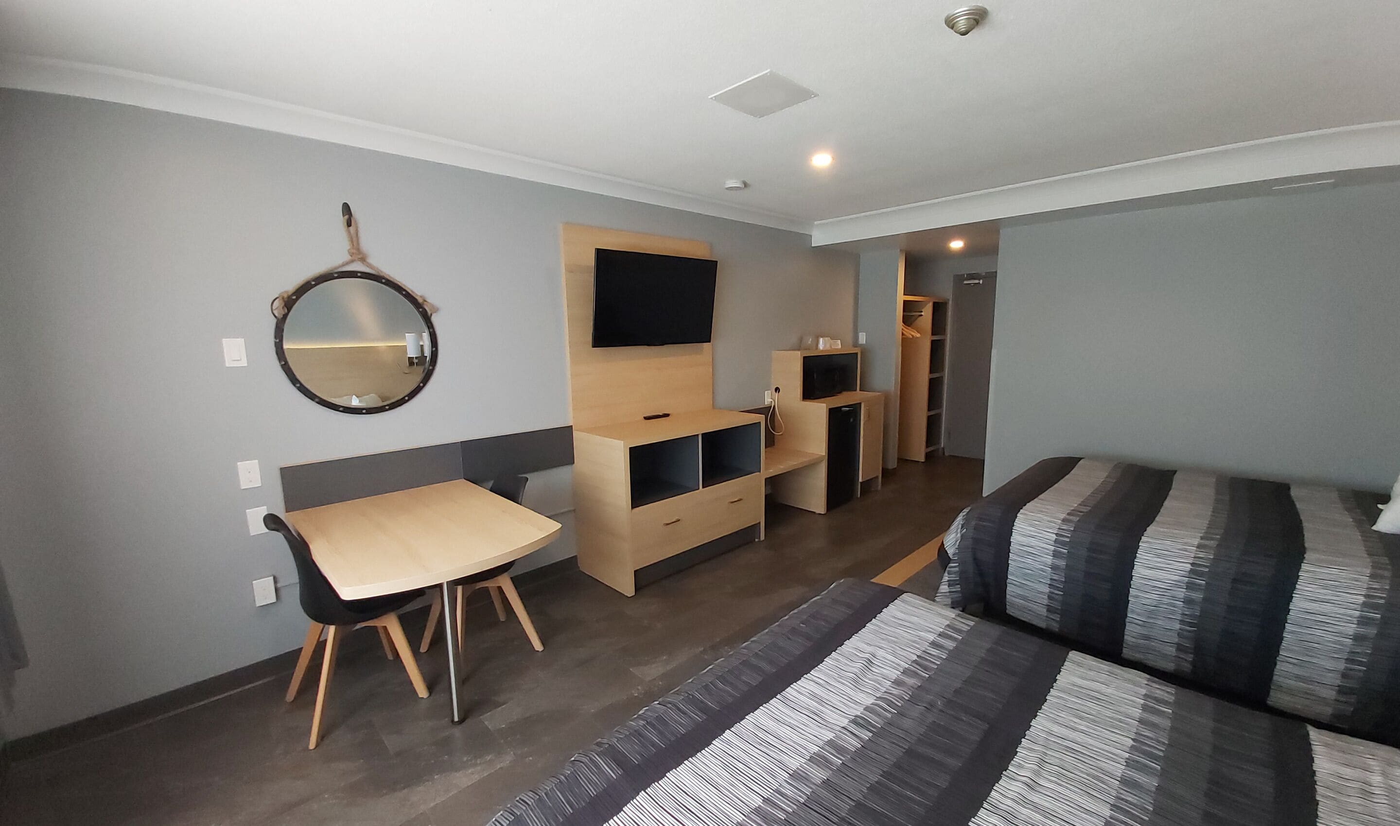 A compact hotel room with a bed, a desk, a mirror, a TV, and a wardrobe.