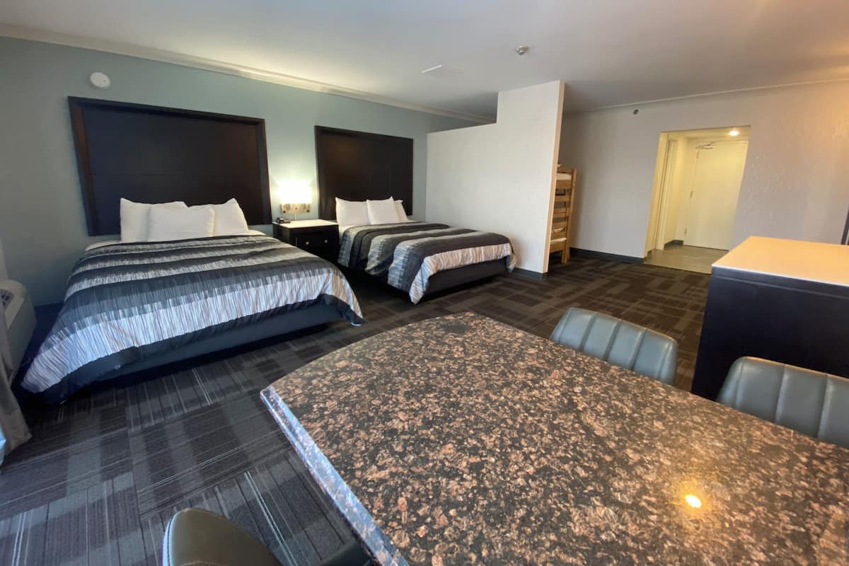 Una habitación de hotel con dos camas, una mesita pequeña y una zona de estar.