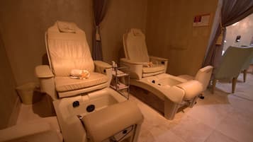 Une salle de spa équipée de deux fauteuils de massage, d’une petite table avec des bouteilles et d’une poubelle.