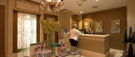 A reception area with a chandelier, a reception desk, and a glass table with brochures.