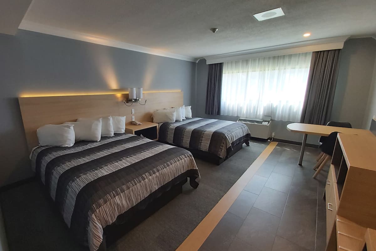 Habitación de hotel con dos camas, un escritorio y una silla.