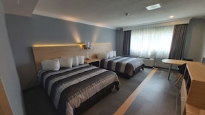 Habitación de hotel con dos camas, un escritorio y una silla.