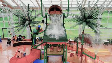 Un área de juegos acuáticos en interior con toboganes y una fuente.