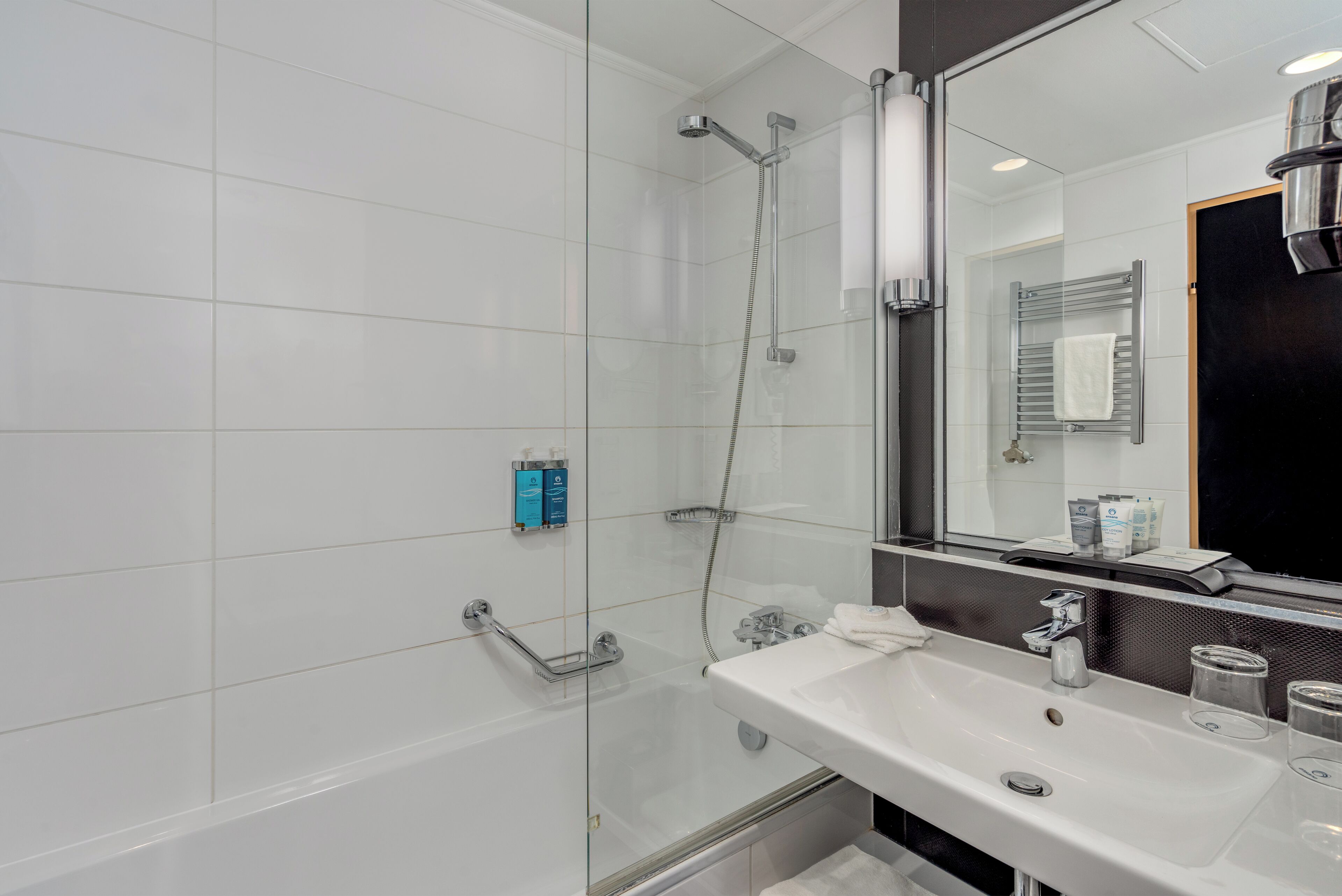 A modern bathroom with a glass-enclosed shower, a white sink, and a large mirror.