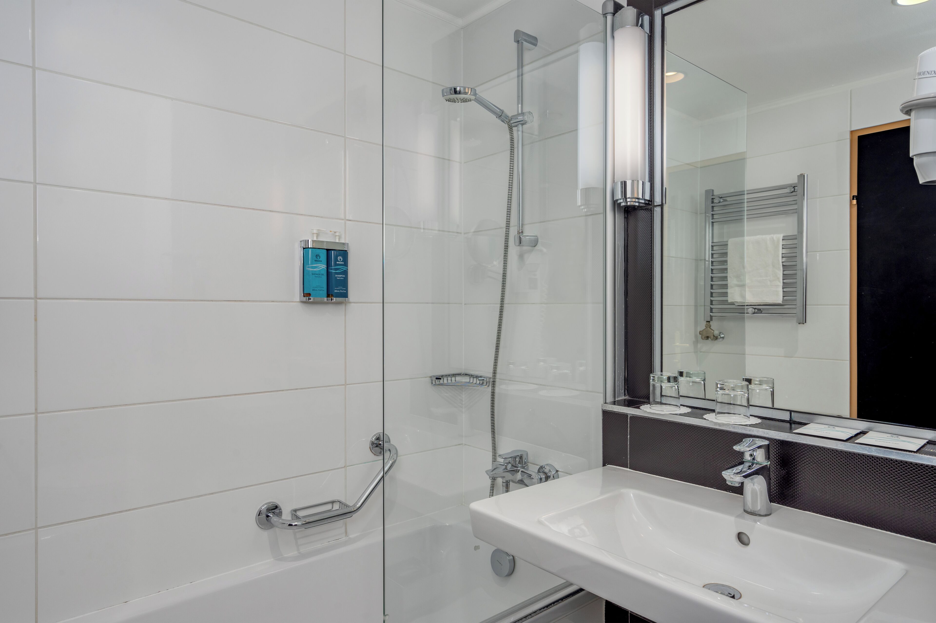 Un baño moderno con ducha envuelta en vidrio, un lavamanos blanco y un espejo grande.