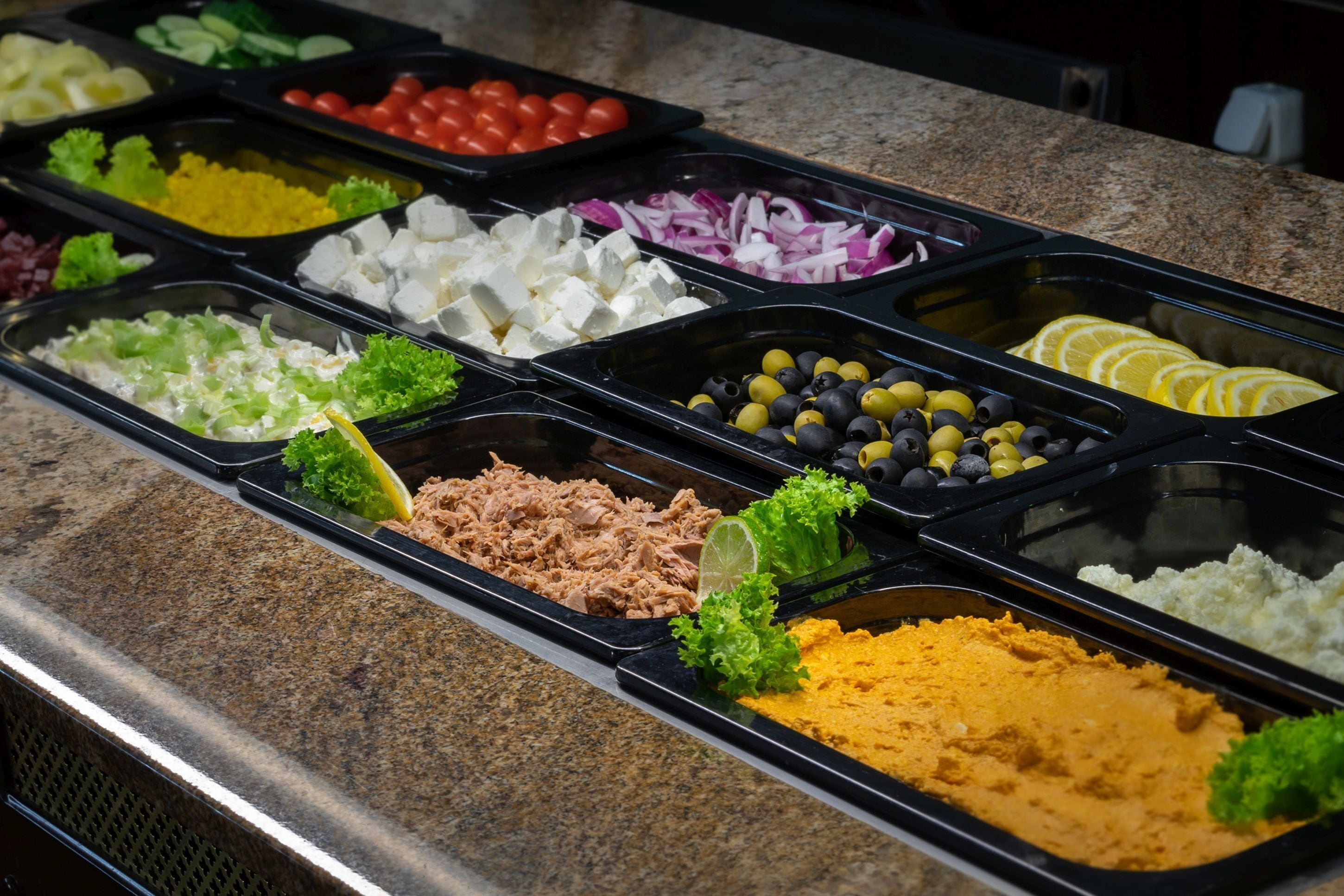 A buffet with various food items including meats, cheeses, and vegetables.