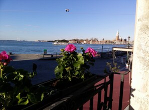 Vista para a orla marítima com um barco, uma ponte e um edifício com uma torre.
