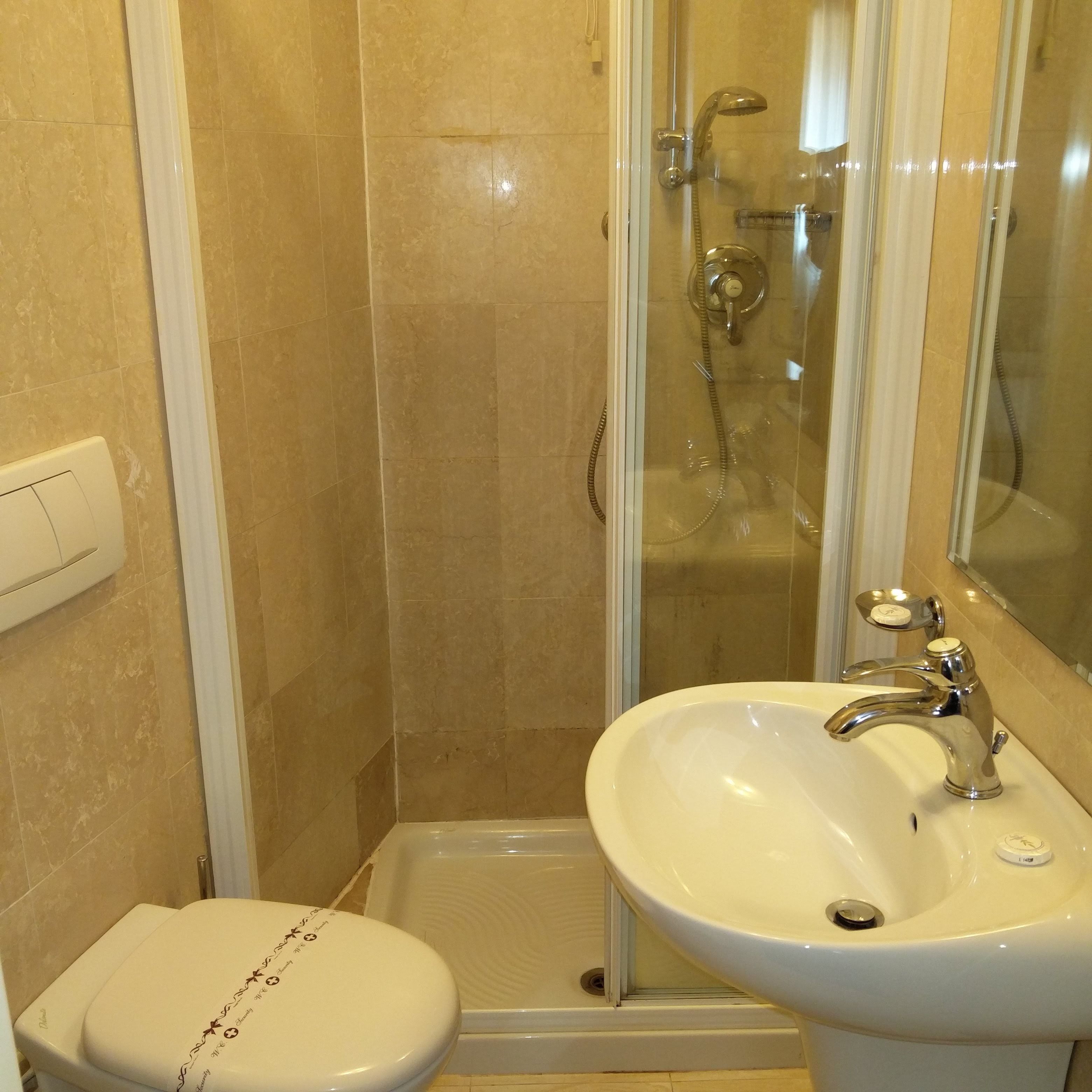 A bathroom with a shower, toilet, and sink.