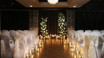 A wedding aisle with white chairs, floral arrangements, and candles.