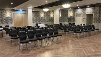 A conference room with rows of black chairs, a white table, and patterned wallpaper.