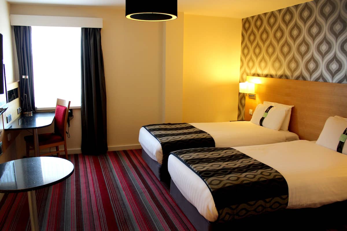 Una habitación de hotel con dos camas, un escritorio y una silla.