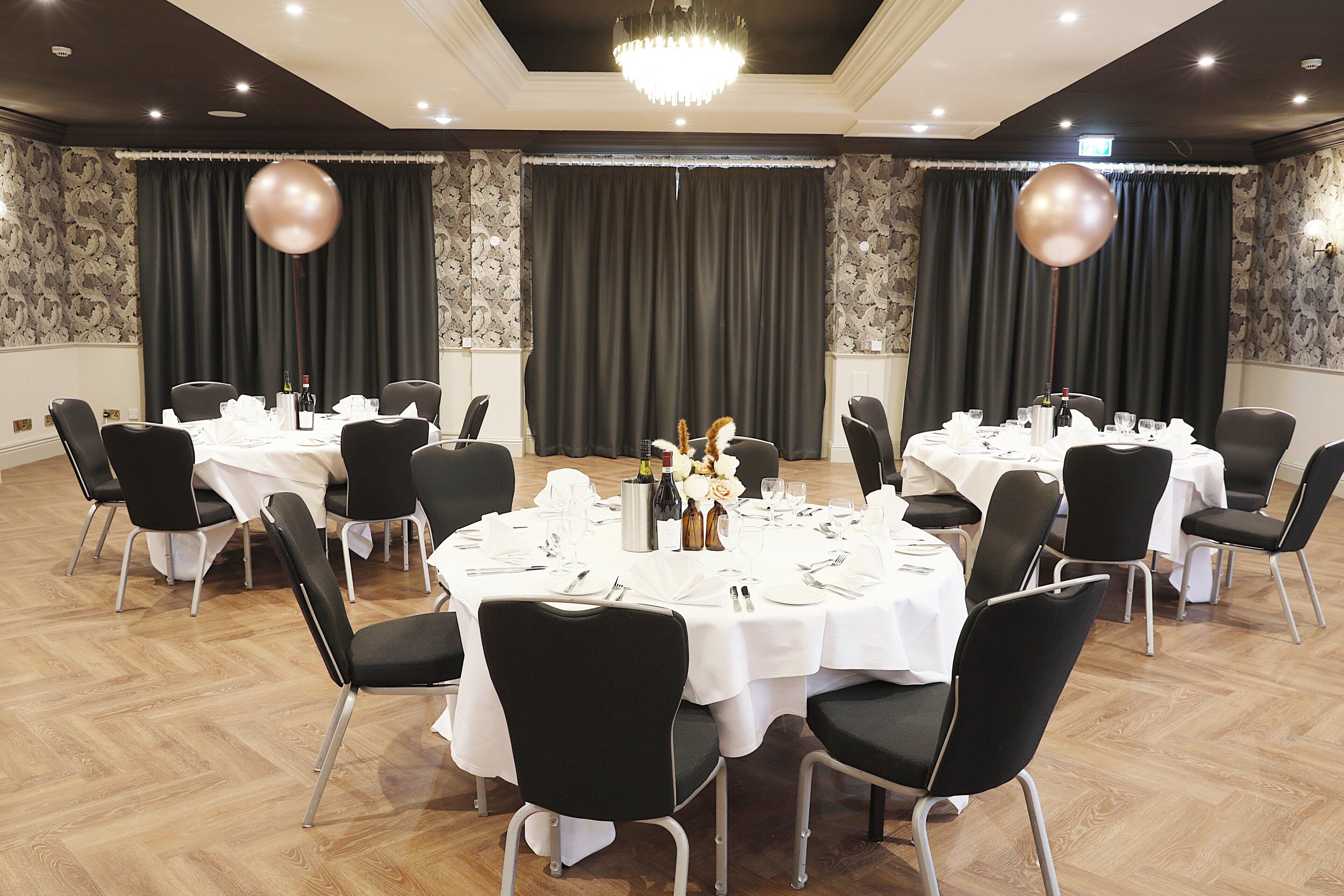 A conference room with multiple tables set for a meeting, each with chairs, white tablecloths, and centerpieces.