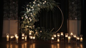 A dark room with a floral arch and candles on a table. - Holiday Inn Newcastle Jesmond by IHG (Newcastle-upon-Tyne)