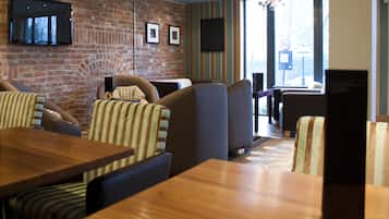 Un restaurant aux murs de briques, aux chaises à motifs rayés et aux tables en bois.