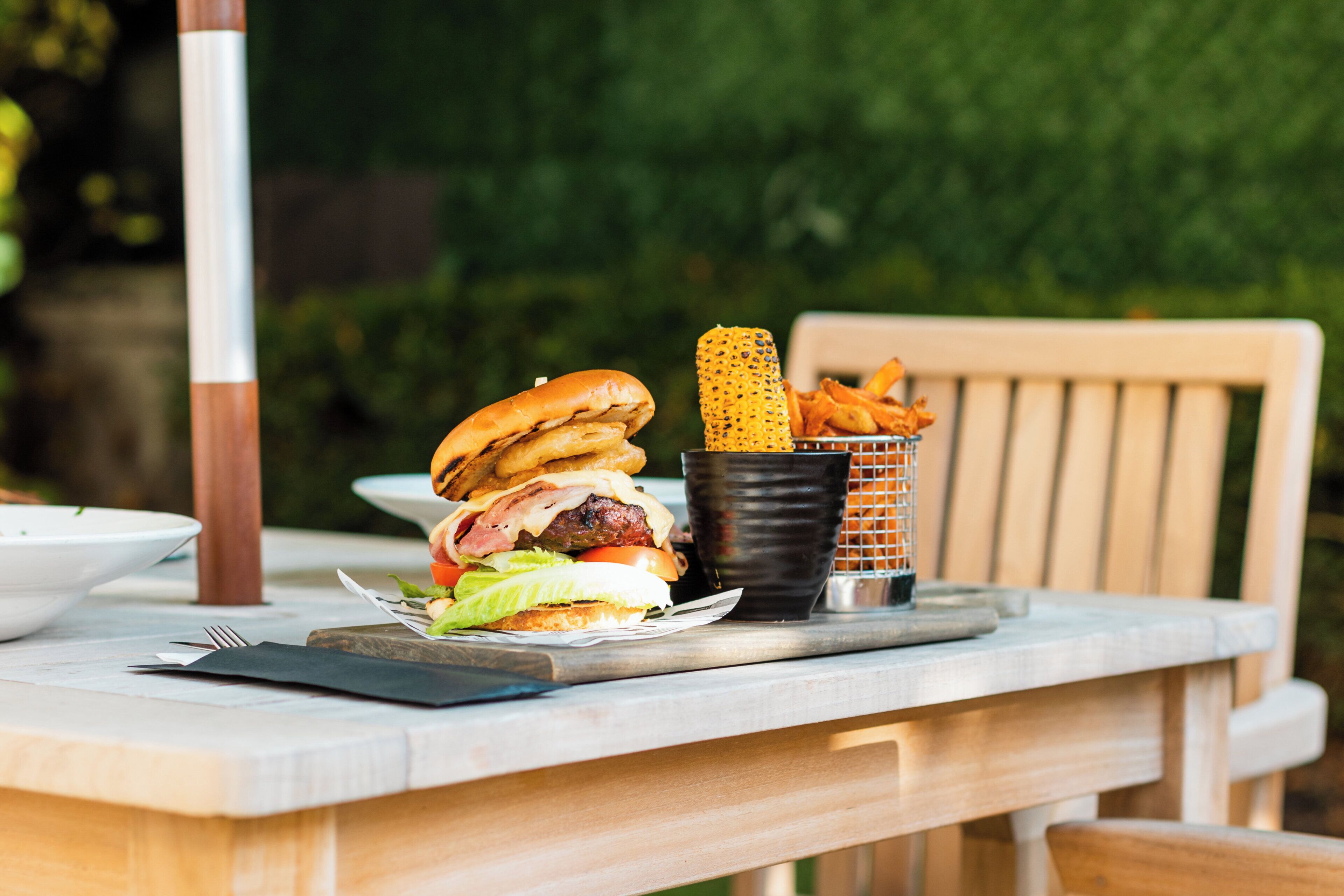 A meal consisting of a burger, two burgers, a cup of fries, and a basket of fries on a table.