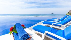 Zona de piscina con sillas de descanso y una toalla azul.