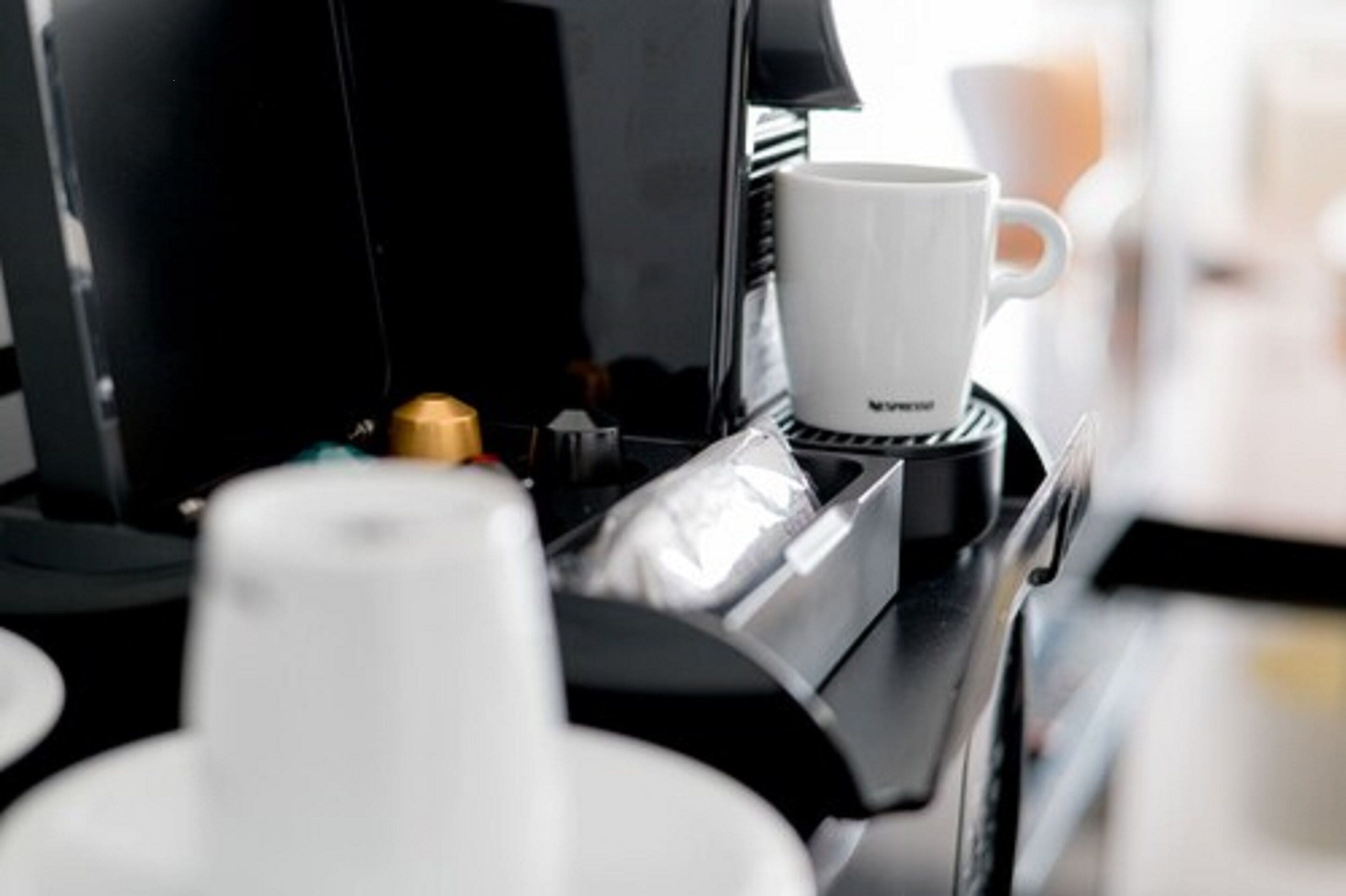 A coffee machine with a white cup on the counter.