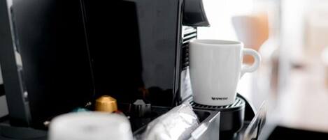 Una cafetera con una taza blanca sobre la encimera.