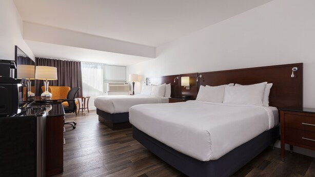 Une chambre d’hôtel avec deux lits, un bureau avec un ordinateur, une chaise et une petite table.